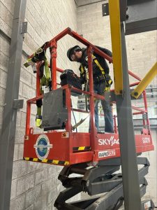 Workers in a factory or industrial setting using safety equipment (helmets, goggles, protective gear).